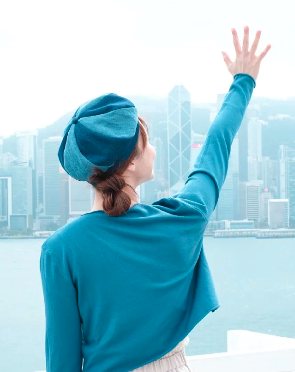 Back view of model waving with teal Sunshine Beret in Hong Kong at Grandmama Store in Hong Kong