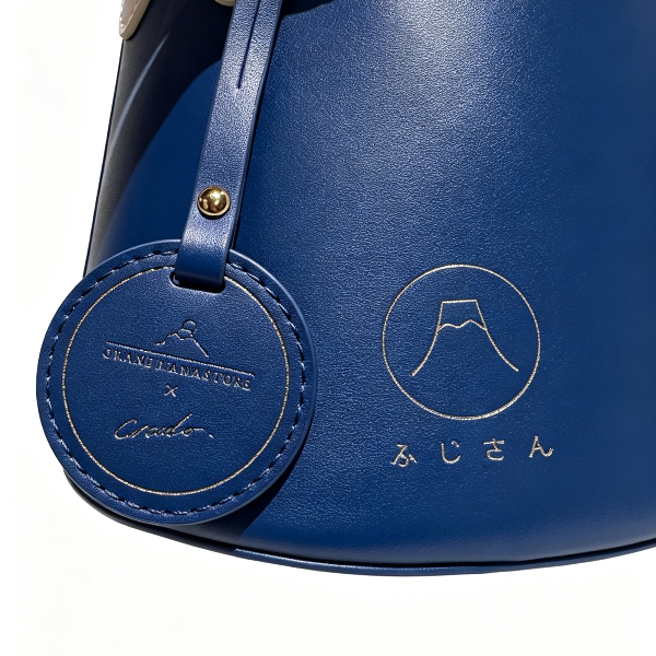Close-up logo and engraved tag on navy Mt. Fuji Goen Bag at Grandmama Store in Hong Kong