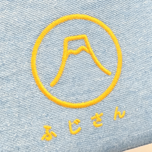 Close-up of yellow embroidered logo on light blue canvas at Grandmama Store in Hong Kong