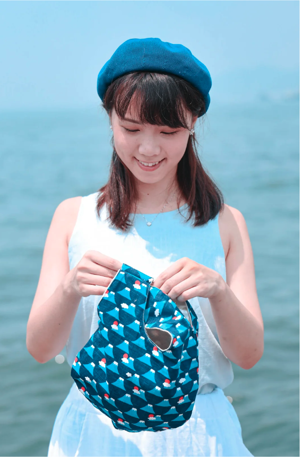 Model closing the magnetic snap on a Blue Fuji Moonshell Bag at Grandmama Store in Hong Kong