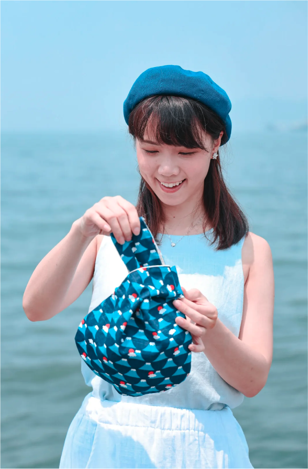 Model holding a Blue Fuji Moonshell Bag by the sea at Grandmama Store in Hong Kong