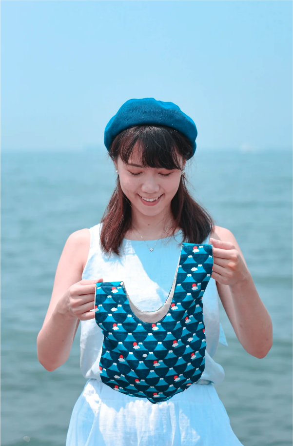 Model holding open the vest-shaped Blue Fuji Moonshell Bag at Grandmama Store in Hong Kong