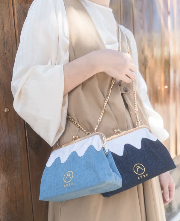 Model holding the Light Blue and Dark Blue denim Mt. Fuji Pocket Bags with gold chain straps at Grandmama Store in Hong Kong.