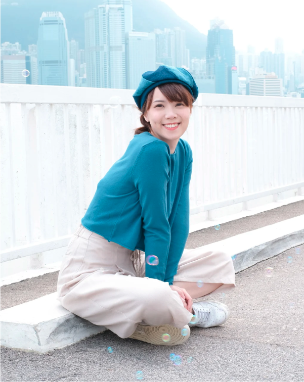 Model wearing a teal Sunshine Beret sitting against the Hong Kong skyline at Grandmama Store in Hong Kong