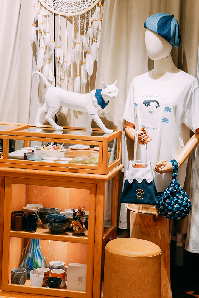 Store interior display showcasing a mannequin with Mt. Fuji canvas tote bag and wooden glass display case at Grandmama Store in Hong Kong.