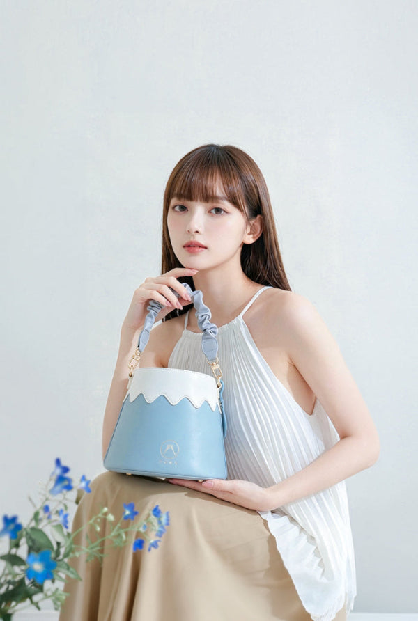 Model holding a light blue and white leather Mt. Fuji Goen Bag in Snow colourway at Grandmama Store in Hong Kong.